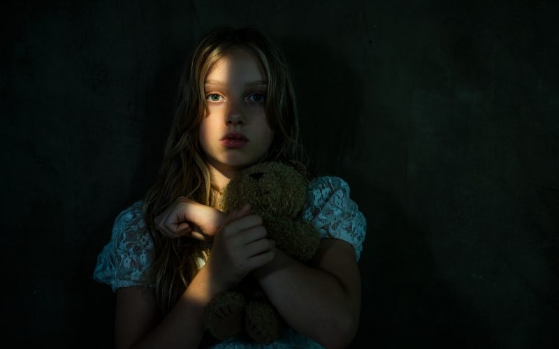 Pige i mørke med en enkelt streg af lys over ansigtet