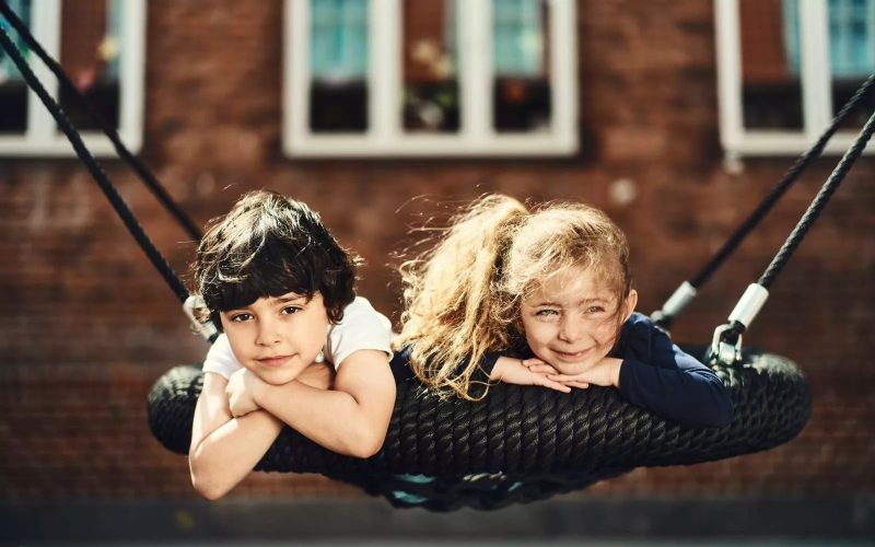 To børn ligger i en gynge og smiler