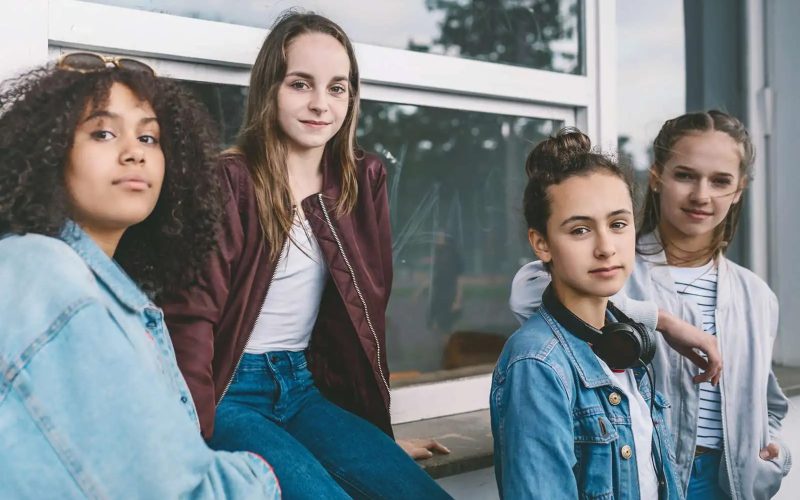 Fire unge piger står op ad en væg