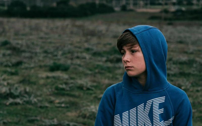 Dreng i blå hoodie står på en mark