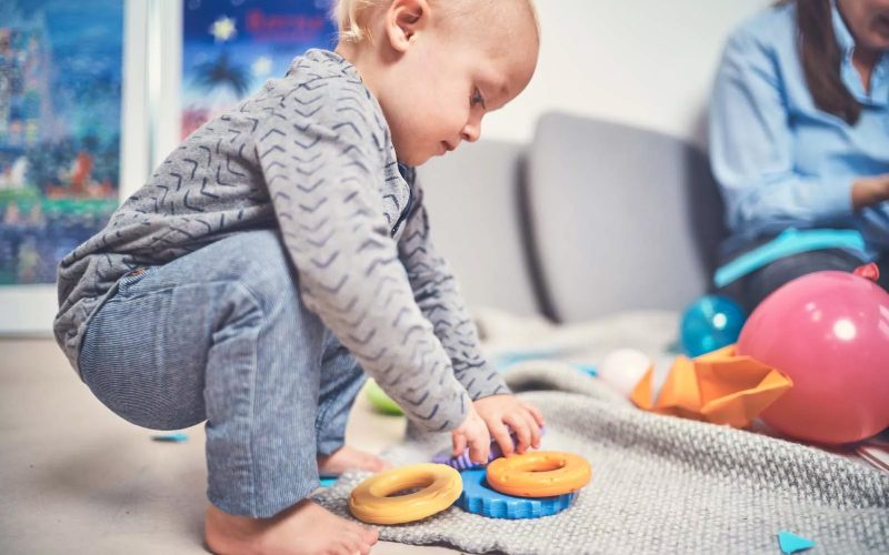 Lille barn leger med legetøjsringe på gulvet