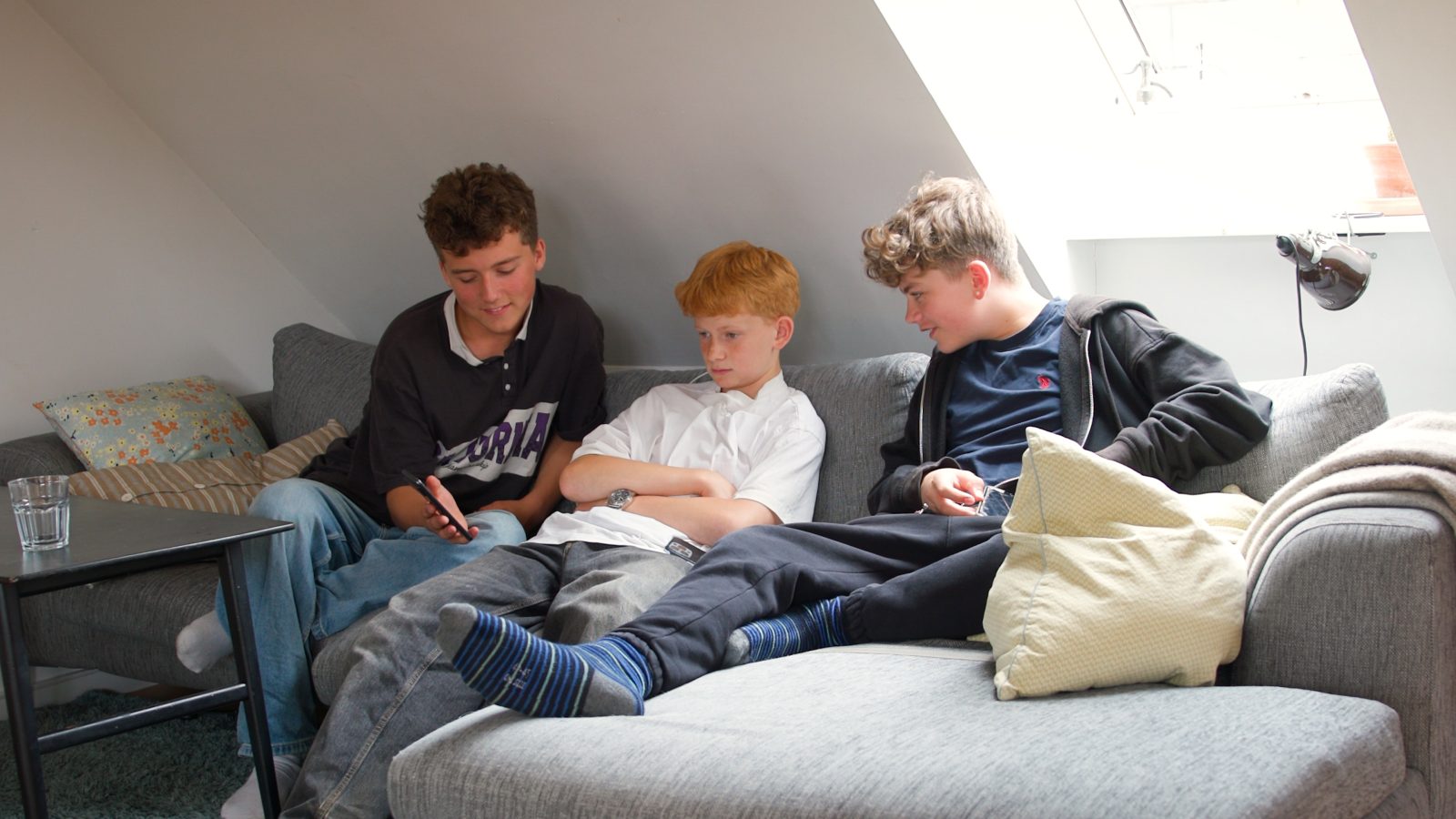 Tre drenge sidder i en sofa