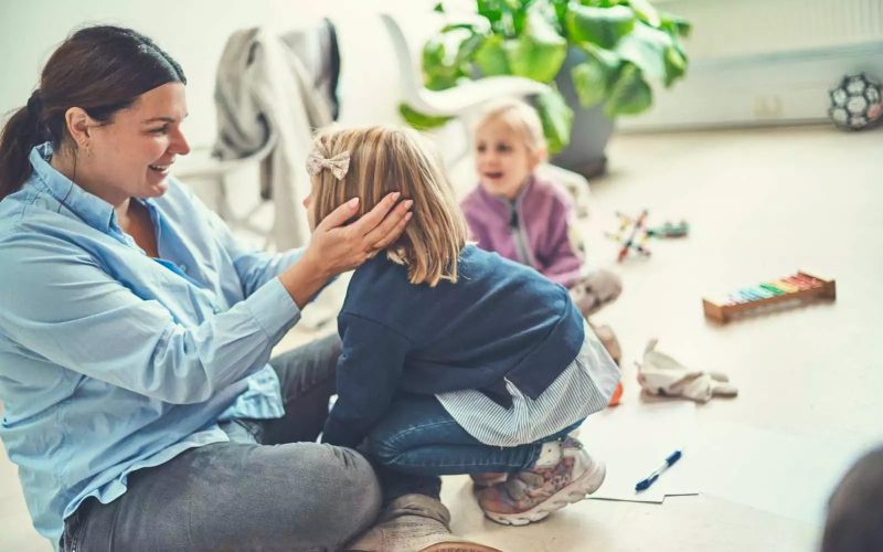 Kvinder sidder på gulvet med et barns hoved i hænderne