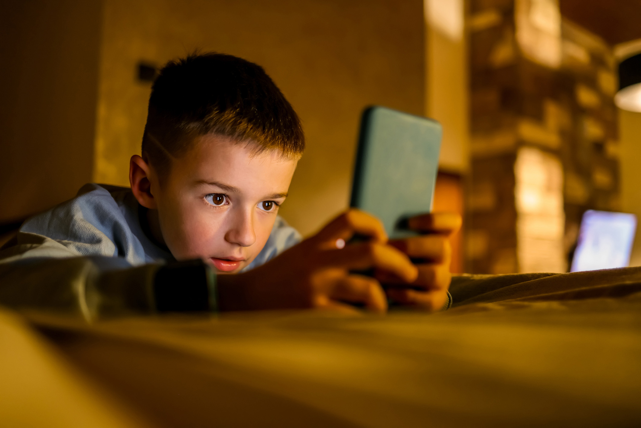 Dreng der ligger på en seng og kigger på sin telefon®é